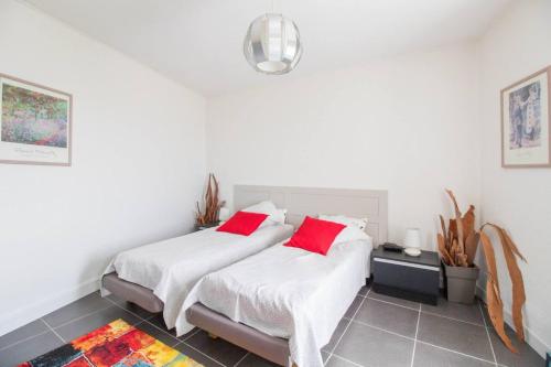 2 Betten in einem Zimmer mit weißen Wänden und roten Kissen in der Unterkunft Les Hauts de Thiers in Thiers