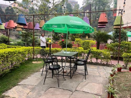 een tafel met stoelen en een groene parasol bij Hotel View Salleri in Kathmandu