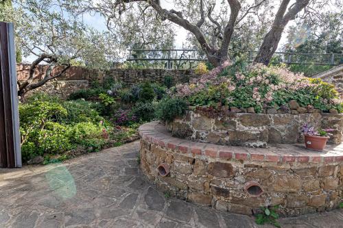 a garden with a stone wall with flowers and plants at Bellezza In Cilento Panoramic Apts in Castellabate