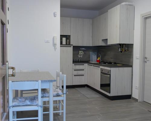 a kitchen with white cabinets and a table and chairs at Appartamento La Corte in Levico Terme