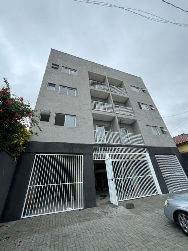 a large building with white gates and a car parked in front at Flat Braganca in Bragança Paulista