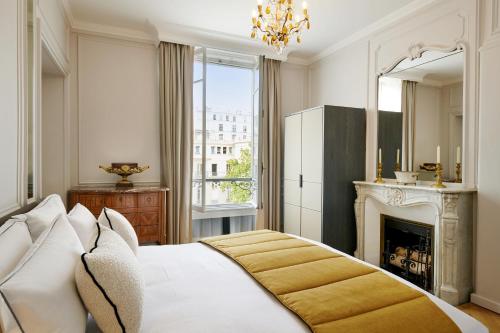 a bedroom with a white bed and a fireplace at Hôtel Lancaster Paris Champs-Elysées in Paris