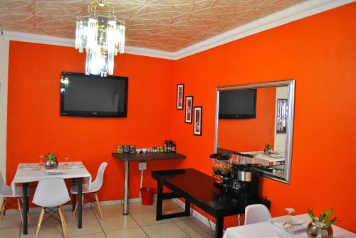 een eetkamer met oranje muren en een tafel en een spiegel bij Lapologa Bed & Breakfast in Tzaneen