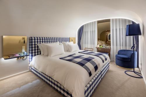 a bedroom with a large bed and a blue chair at Hästens Sleep Experience FLH Hotels Coimbra in Coimbra