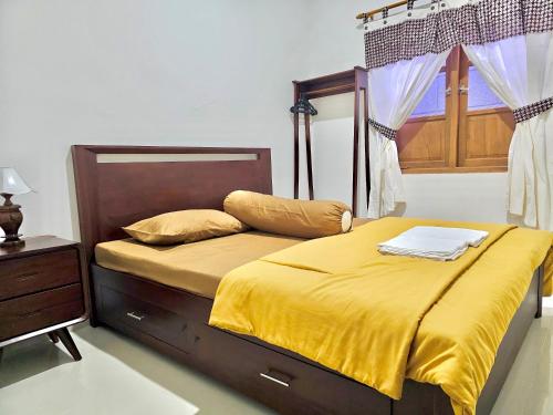 ein Schlafzimmer mit einem Bett mit gelber Bettwäsche und einem Fenster in der Unterkunft Omah Tabon Jogja - Dekat Dengan Malioboro in Timuran