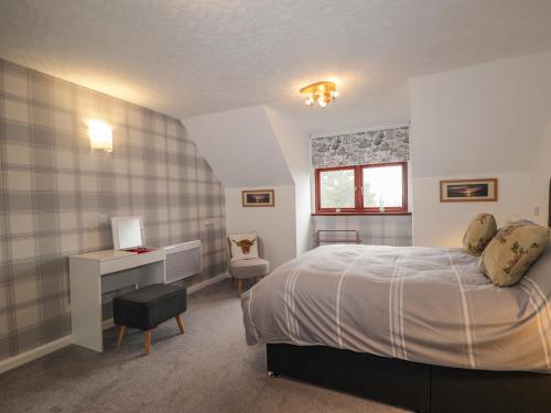a bedroom with a bed and a desk and a window at Purlie Lodge Apartment in Inverness