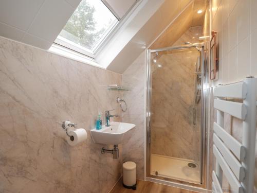uma casa de banho com um chuveiro e um lavatório. em Purlie Lodge Apartment em Inverness