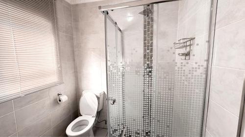a bathroom with a toilet and a glass shower at Contemporary Gem: Studio with Serene Pool View in Newcastle
