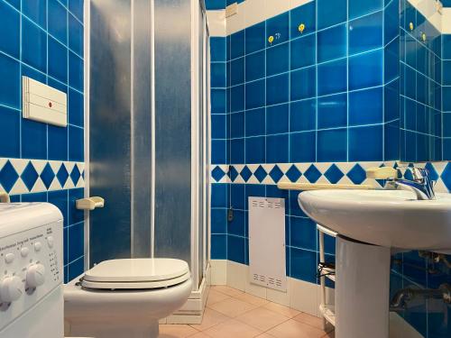 a blue tiled bathroom with a toilet and a sink at Appartamento in complesso con piscina in Santa Teresa Gallura