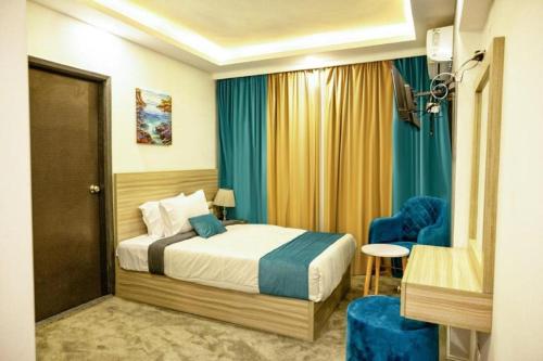 a bedroom with a bed and two blue chairs at Mar Charbel Hotel Cairo in Cairo