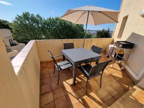 une table et des chaises avec un parasol sur une terrasse dans l'établissement SUPERBE appartement T3 avec extérieur à 50m de la mer, à Saint Pierre La Mer