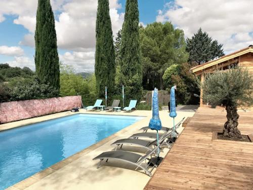 une piscine avec chaises longues et parasols dans l'établissement Maison familiale avec piscine partagée à Saint-André-de-Cruzières, à Saint-André-de-Cruzières