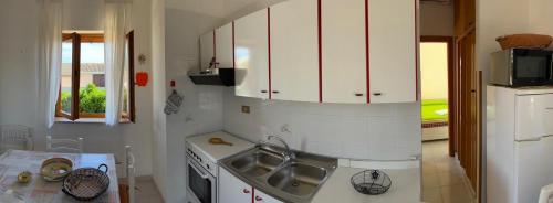 cocina con armarios blancos, fregadero y fogones en New Residence, en Buonfornello