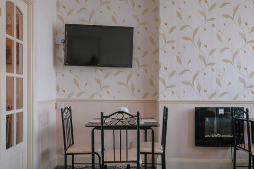 a dining room with a table and a television on a wall at The Kildare in Skegness