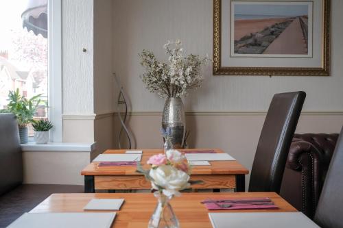 a dining room table with a vase of flowers on it at The Kildare in Skegness