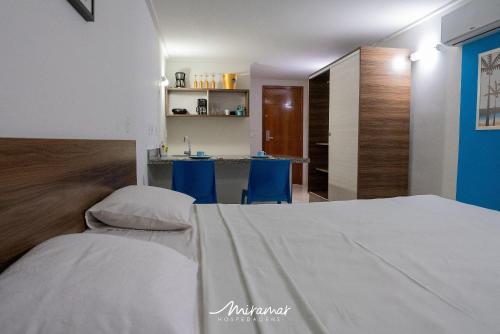 a bedroom with a white bed and blue chairs at Blue Sunset in Penha