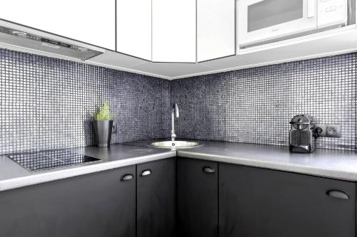 une cuisine avec des armoires blanches et un évier dans l'établissement Lovely top floor studio near Montmartre, à Paris