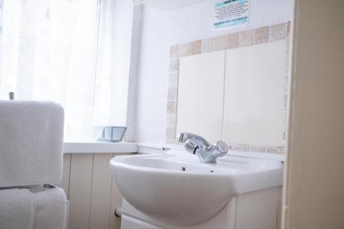 a white bathroom with a sink and a window at The Kildare in Skegness