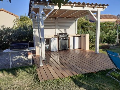 eine Holzterrasse mit einem Grill und einer Küche im Freien in der Unterkunft Haut de villa avec jardin (Apt T3) in Bormes-les-Mimosas