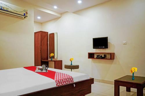 a bedroom with a bed and a tv on the wall at Hotel Swapna in Vijayawāda