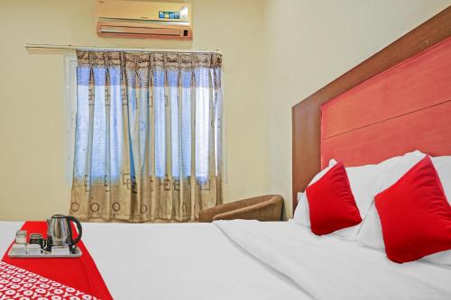 a bedroom with a bed with red pillows and a window at Hotel Swapna in Vijayawāda