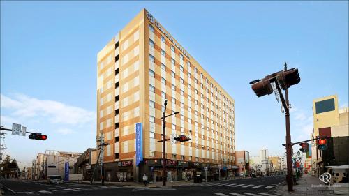 a tall building on a city street with traffic lights at Daiwa Roynet Hotel Hachinohe in Hachinohe
