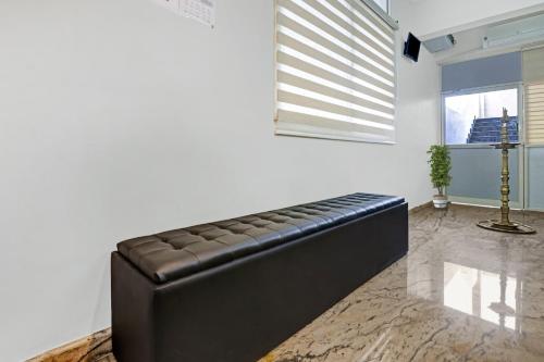 - un canapé en cuir noir dans une chambre avec fenêtre dans l'établissement OYO Poptavern Premium, à Trivandrum