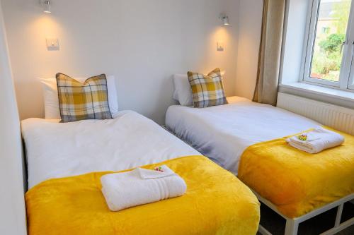 Dings Village Corner House by StayStaycations في بريستول: سريرين في غرفة صغيرة ذات وسائد صفراء