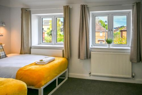 a bedroom with a bed and two windows at Dings Village Corner House by StayStaycations in Bristol