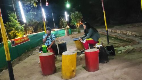 a man and a woman sitting next to trash cans at Camp Moonlight beauty in Nainital