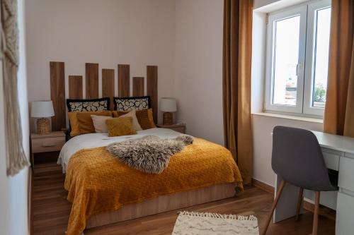 a bedroom with a bed with an orange blanket and a desk at Stone House With Jacuzzi "DINARA" in Kijevo
