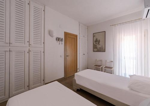 a white bedroom with two beds and a window at PGS IMMOBILIARE SRLS – Pagello D – Trilocale vista mare– La Maddalena in Casale Azara