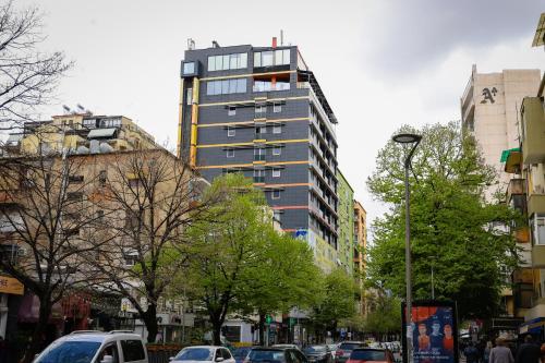 a tall building on a city street with cars at La Bohème Hotel in Tirana