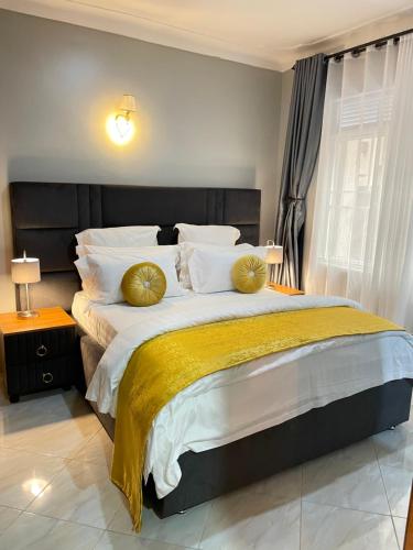 a bedroom with a large bed with gold pillows at Athena Apartments in Kampala