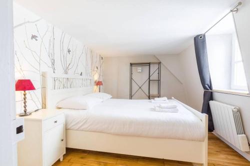 a white bedroom with a white bed and a window at Le Duplex des Ducs in Dijon