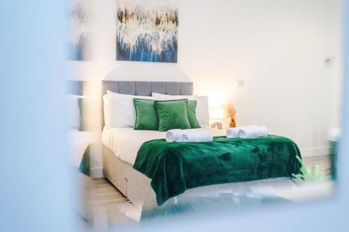 a bedroom with a bed with a green blanket at Old Bank Studio Apartments in Bolton