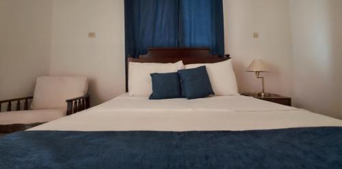 a bedroom with a large bed with blue pillows at Rainbow Inn in Grand Bras