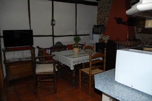 a dining room with a table and chairs and a tv at Apartamentos Rurales Tía Josefa in Tornavacas