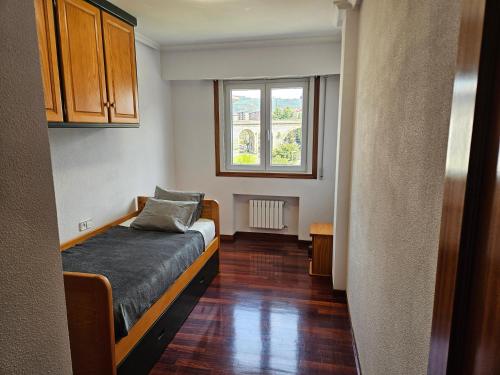 um pequeno quarto com uma cama e uma janela em Pirámides Ourense em Ourense