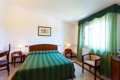 a bedroom with a bed and two chairs and a window at Hotel Villa d'Amato in Palermo