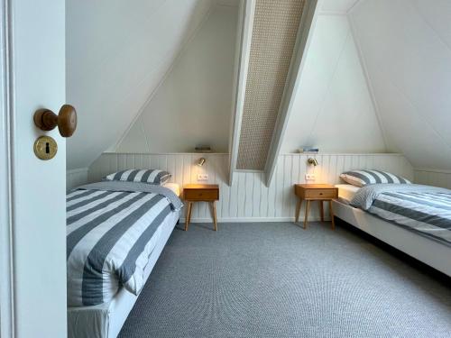 a attic bedroom with two beds and two lamps at Herberg Het Rechthuis in Rinsumageest