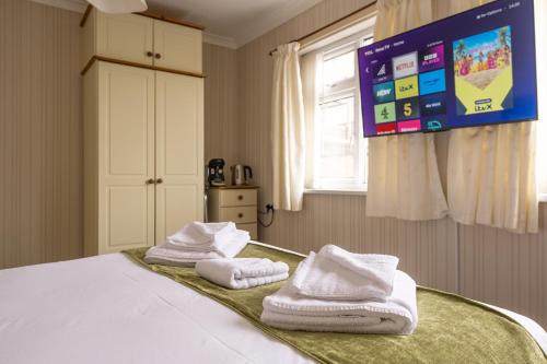 a bedroom with towels on a bed with a tv at The Kildare in Skegness