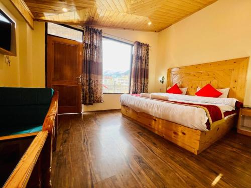 a bedroom with a large bed and a large window at The Royal View Cottage in Manāli