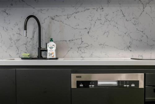 a kitchen counter with a sink and a bottle of detergent at Park Ave City delight in Canberra