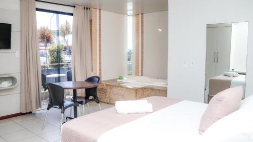 1 dormitorio con 2 camas, mesa y balcón en Hotel Sol Nascente en Arapiraca