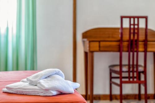 a pile of towels sitting on a bed next to a desk at Hotel Villa d'Amato in Palermo