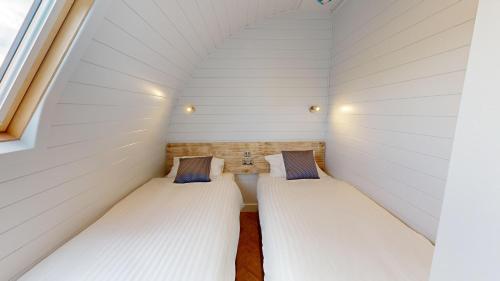 twee bedden in een kleine kamer met een raam bij Bromach Lodge in Latheron