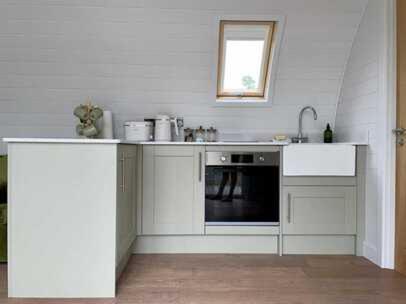 a white kitchen with a sink and a stove at Bromach Lodge in Latheron