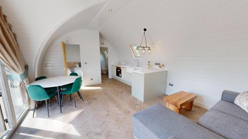 a kitchen and living room with a table and green chairs at Bromach Lodge in Latheron