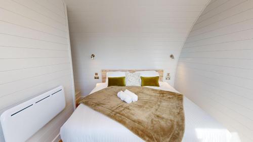 a small bedroom with a bed with white sheets and yellow pillows at Bromach Lodge in Latheron